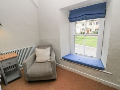 A snug with an armchair and a window at Ostlers in Burford