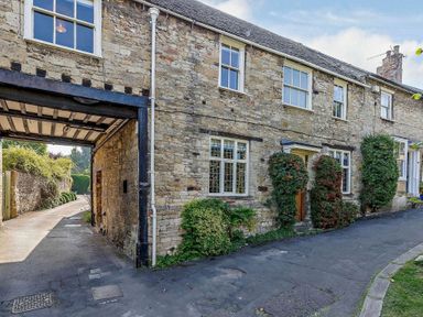 An outdoor view of a stone building with windows and plants at Ostlers Burford