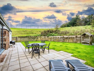 A garden with table and chairs at Beachcombers in Marhamchurch