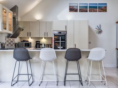 A kitchen with a sink and stools at Beachcombers in Marhamchurch