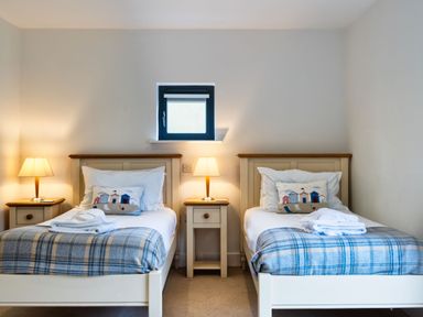 A bedroom with two beds and lamps at Beachcombers in Marhamchurch
