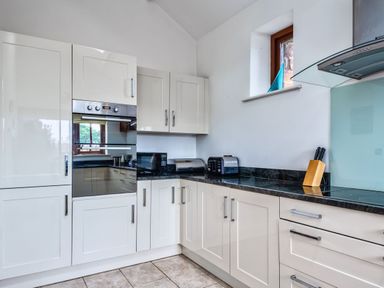 A kitchen with cabinets and appliances at Woodyplatt in Marhamchurch