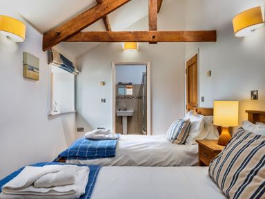A bedroom with two beds and a bathroom visible at Woodyplatt in Marhamchurch