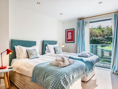 A bedroom with two beds and a balcony at Chapel Park in Marhamchurch