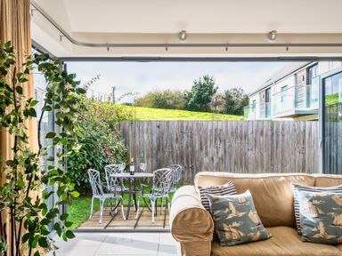 A living room with a view of an outdoor seating area at Little Main in Marhamchurch