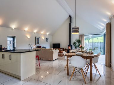 A living room with a dining area and kitchen island at Little Main in Marhamchurch