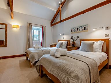 A bedroom with two beds and a window at Long Down Spa in Marhamchurch