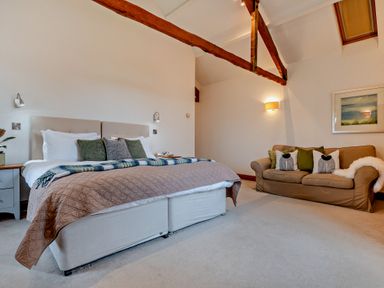 A bedroom with a bed and a sofa at Long Down Spa in Marhamchurch