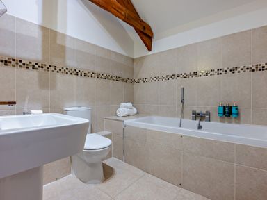 A bathroom with a bathtub, toilet, and sink at Middle Hill in Marhamchurch