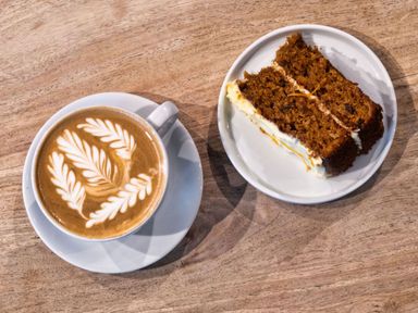 A coffee with latte art and a slice of cake on a plate
