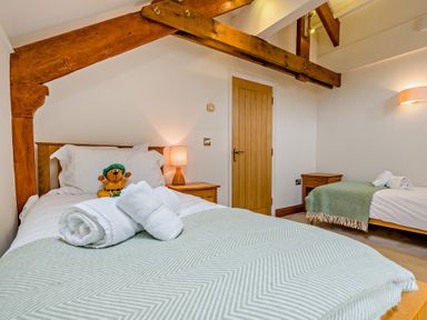 A bedroom with two beds and a teddy bear at Sand Parks in Marhamchurch