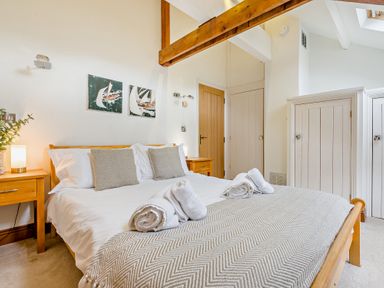 A bedroom with a bed, bedside table, and wardrobe at Sand Parks in Marhamchurch