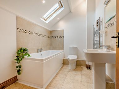 A bathroom with a bathtub, toilet and sink at Sand Parks in Marhamchurch