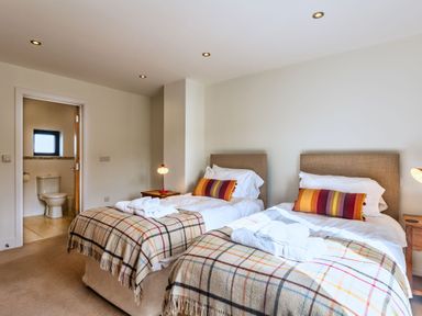 A bedroom with twin beds and an adjoining bathroom at Venners in Marhamchurch