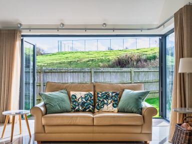 A snug with a sofa and large open doors at Warrens Spa Marhamchurch