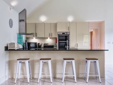 A kitchen with bar stools and appliances at Warrens Spa in Marhamchurch