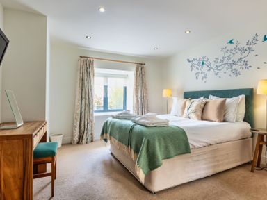 A bedroom with a bed and dresser at Warrens Spa Marhamchurch