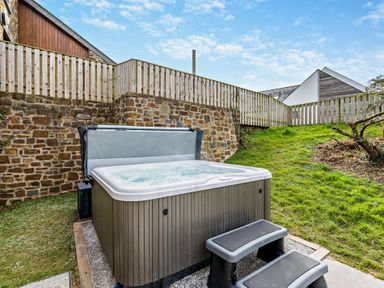 A hot tub with steps in a garden at Warrens Spa in Marhamchurch