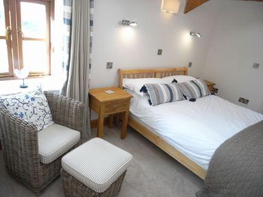 A bedroom with a bed and chairs at Westcotts in Marhamchurch