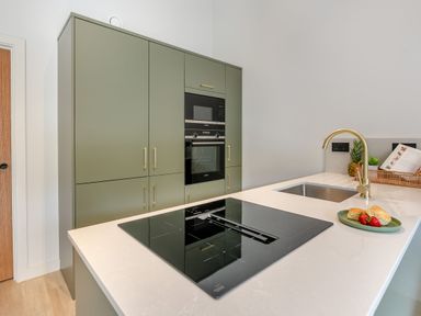 A kitchen with green cabinets and a stove at Gwari Spa Barn 2.0 in Marhamchurch