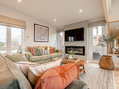 A living room with a sofa, coffee table, and television at Trelowen 2.0 Spa in Marhamchurch