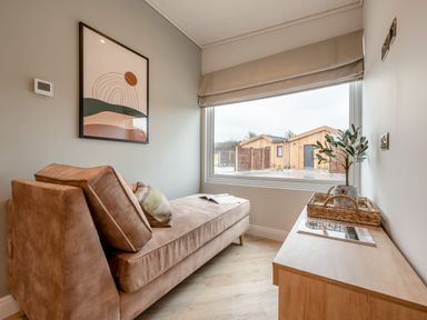 A snug with a sofa, side table, and window view at Trelowen 2.0 Spa in Marhamchurch