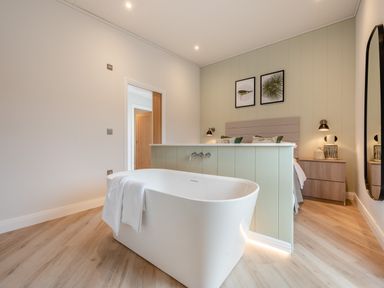 A bathroom with a bathtub and a bed at Trelowen 2.0 Spa in Marhamchurch