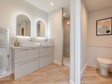 A bathroom with sinks, mirrors, and a shower at Trelowen 2.0 Spa in Marhamchurch
