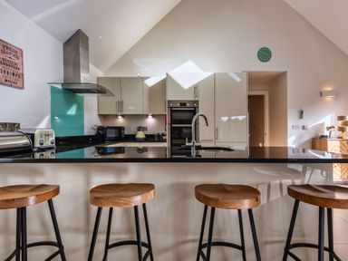 A kitchen with bar stools and kitchen appliances at Nettlecoombe Spa in Marhamchurch