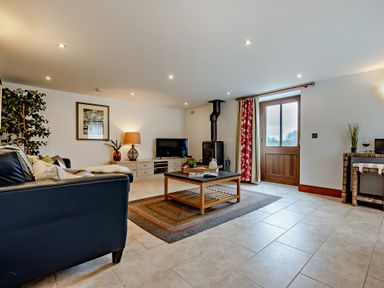 A living room with a sofa, coffee table, and television at Jack's House in Marhamchurch