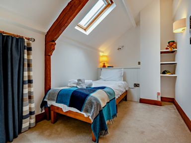 A bedroom with a bed and shelves at Jack's House in Marhamchurch