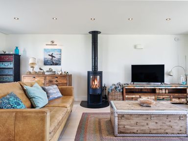 A living room with a fireplace and sofa at Eagle's Nest in Marhamchurch
