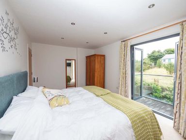 A bedroom with a bed and wardrobe at Medlands in Marhamchurch