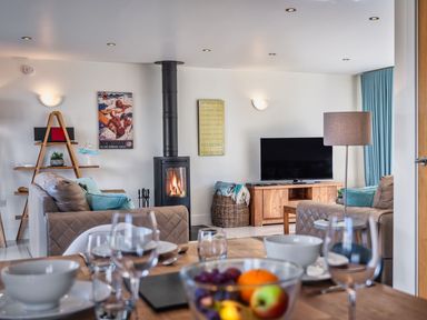 A living room with a sofa, TV, and fireplace at Sheep's House in Marhamchurch