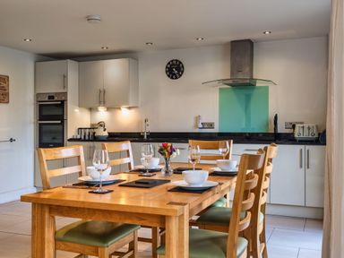 A kitchen with a dining table and chairs at Trevelyan in Marhamchurch