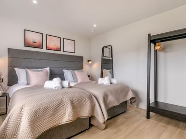 A bedroom with two beds and a clothes rack at Gwari Spa Barn 3.0 in Marhamchurch