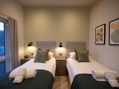A bedroom with twin beds and bedside table at Trelowen 3.0 Spa in Marhamchurch