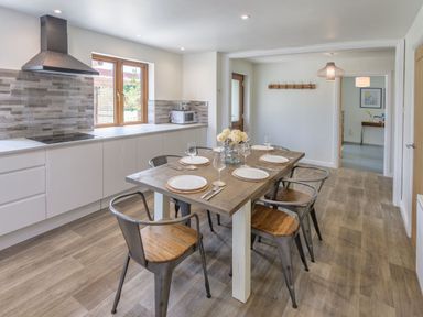 A dining room with a wooden table and chairs at Windy Hills Spa Marhamchurch