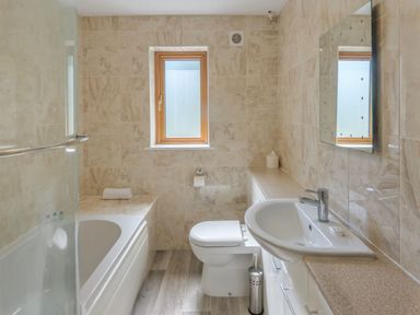 A bathroom with a bathtub, toilet, sink, and window at Windy Hills Spa in Marhamchurch