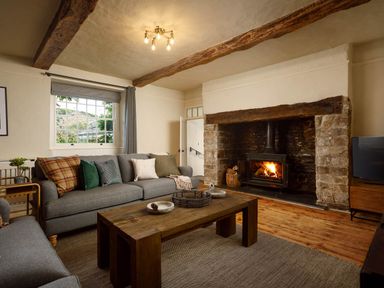A living room with a sofa and fireplace at Whalesborough Farmhouse Spa in Marhamchurch