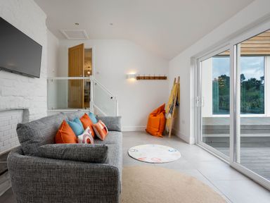 A living room with a sofa and a television at Whalesborough Cottage Spa in Marhamchurch