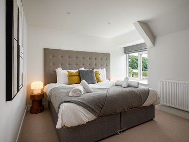 A bedroom with a bed and bedside lamps at Whalesborough Cottage Spa in Marhamchurch