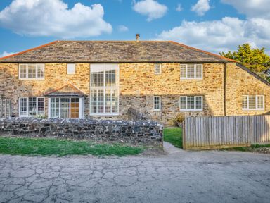A house with stone exterior and multiple windows at Calf House Spa in Marhamchurch