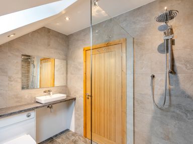 A bathroom with a shower, sink, and mirror at Tranquillity 4 in Carnforth