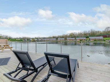 An outdoor area with sun loungers overlooking a lake at Tranquillity 4 (Pet) in Carnforth