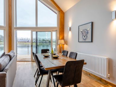 A dining room with a table and chairs overlooking a lake at Tranquillity 4 (Pet) Carnforth
