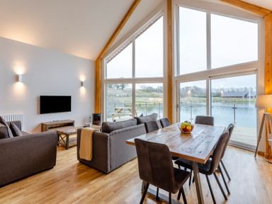 A living room with a sofa, dining table and large windows at Tranquillity 4 (Pet) in Carnforth