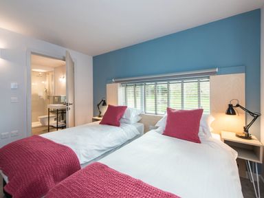 A bedroom with two single beds and a bathroom visible at The Laidlaw in North Berwick