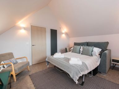 A bedroom with a bed, sofa, and a chair at The Laidlaw in North Berwick