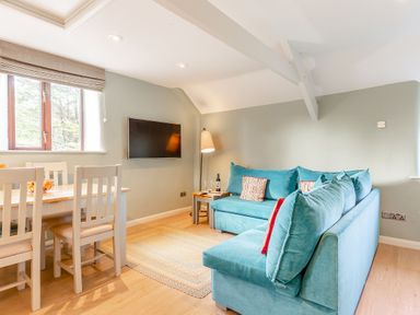 A living room with a sofa and dining area at Crabtree Cottage in Bude